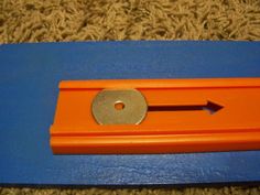 an orange and blue plastic object with a hole in the middle on carpeted area