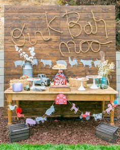 a wooden table topped with lots of cake and desserts next to a sign that says happy birthday