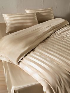 an image of a bed with beige sheets and pillowcases on top of it