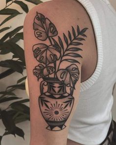 a woman's arm with a vase full of flowers and leaves on the side