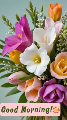 a vase filled with different colored flowers on top of a wooden table next to a sign that says good morning