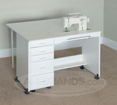 a sewing machine sits on top of a white desk with drawers and wheels in front of it