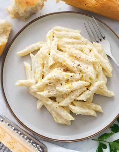 a white plate topped with pasta next to bread