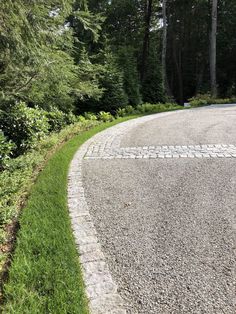 a paved road with grass and trees in the background