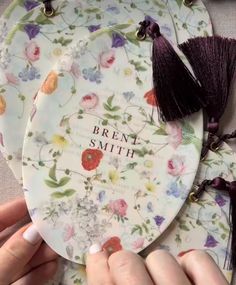 two plates with flowers and tassels are being held by someone's hands