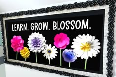 a sign that says learn grow blossom on the side of a wall with flowers painted on it