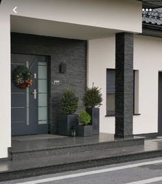 a black and white building with two plants on the steps