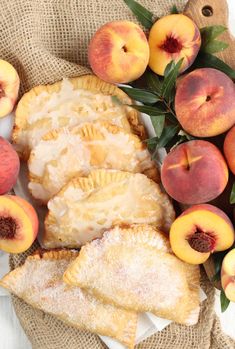 peach pastries on a plate with fresh peaches and leaves next to the pie