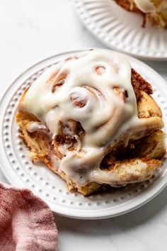 two plates with cinnamon rolls covered in icing