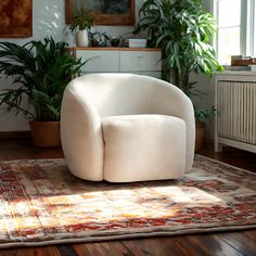 a white chair sitting on top of a wooden floor next to a potted plant