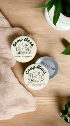 two camp santa buttons sitting on top of a wooden table next to a potted plant