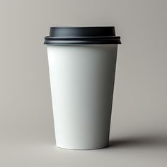 a white coffee cup with a black lid on a gray background is seen from the side