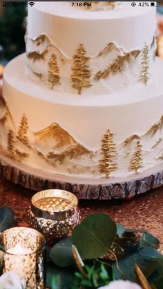 a three tiered wedding cake sitting on top of a table next to greenery