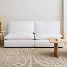 a white couch sitting on top of a rug next to a table and vases