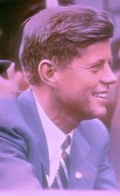 a man wearing a suit and tie sitting next to another man