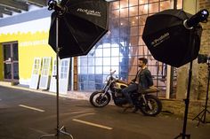 a man sitting on a motorcycle in front of a building with an umbrella over it