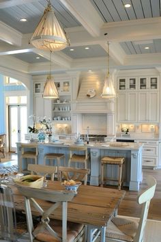 a large kitchen with an island table and chairs in the center, surrounded by white cabinets