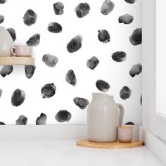 a white vase sitting on top of a counter next to a black and white wall