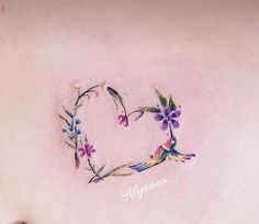 a heart shaped tattoo with flowers and leaves on the back of someone's stomach