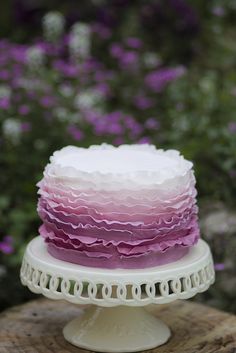 a cake sitting on top of a white plate covered in frosting and ruffles