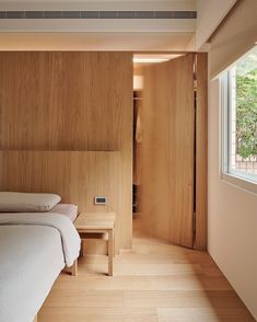 two beds in a room with wooden walls and flooring next to a large window