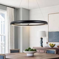 a dining room table and chairs with a bowl of fruit on the table in front of it