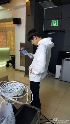 a young man standing in front of a pile of wires and looking at a magazine