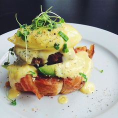 a white plate topped with an open face sandwich covered in cheese and toppings on top of it