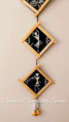 three black and white pictures hanging from the ceiling with bells on each side, one has an image of a person holding a bell