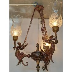 an antique chandelier with glass shades hanging from it's sides and attached to the ceiling