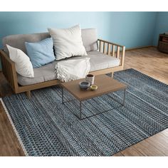 a living room with blue walls and wooden furniture on the floor, including a gray couch