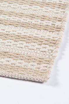 a close up view of a beige and white rug on a white surface with no one in it