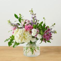 a vase filled with lots of flowers on top of a wooden table