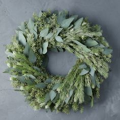 a wreath made out of green leaves and greenery on a gray background with space for text