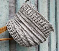 a crocheted hat hanging from a hook on a wooden wall with wood slats in the background