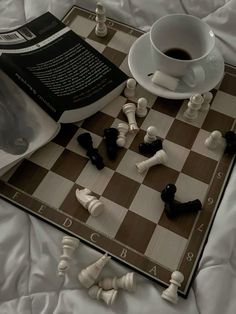 a chess board with black and white pieces on it next to a cup of coffee