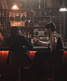 two people sitting at a bar in front of an old fashioned radio and sound equipment