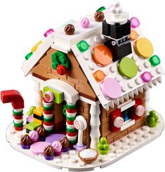 a small building made out of legos on a white surface with candy and candies all over it