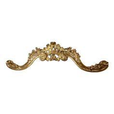 an ornate gold metal handle on a white background