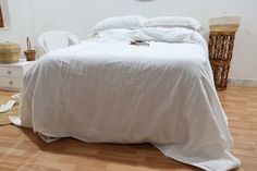 an unmade bed with white sheets and pillows on top of it in a bedroom