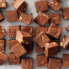 pieces of chocolate fudge with nuts scattered around them on a marble counter top,