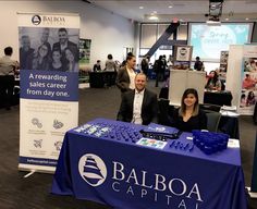 two people sitting at a table in front of a sign that says balboa capital