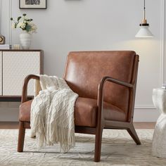 a brown leather chair with a white blanket on top of it in a living room