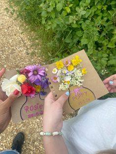 two people holding flowers in their hands and an open book with writing on the cover