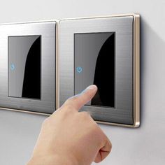 a person pointing at two light switches on the wall with their finger in front of them