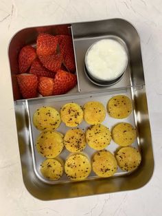 a metal tray filled with pastries and strawberries next to a bowl of yogurt