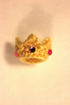 a small yellow crocheted animal with red eyes on a white surface, looking up at the camera