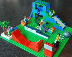 some legos are sitting on a table with green and blue bricks in front of them