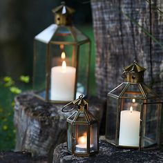 two lit candles sitting on top of a tree stump