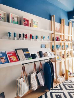 several bags and purses are hanging on the wall next to shelves in a store